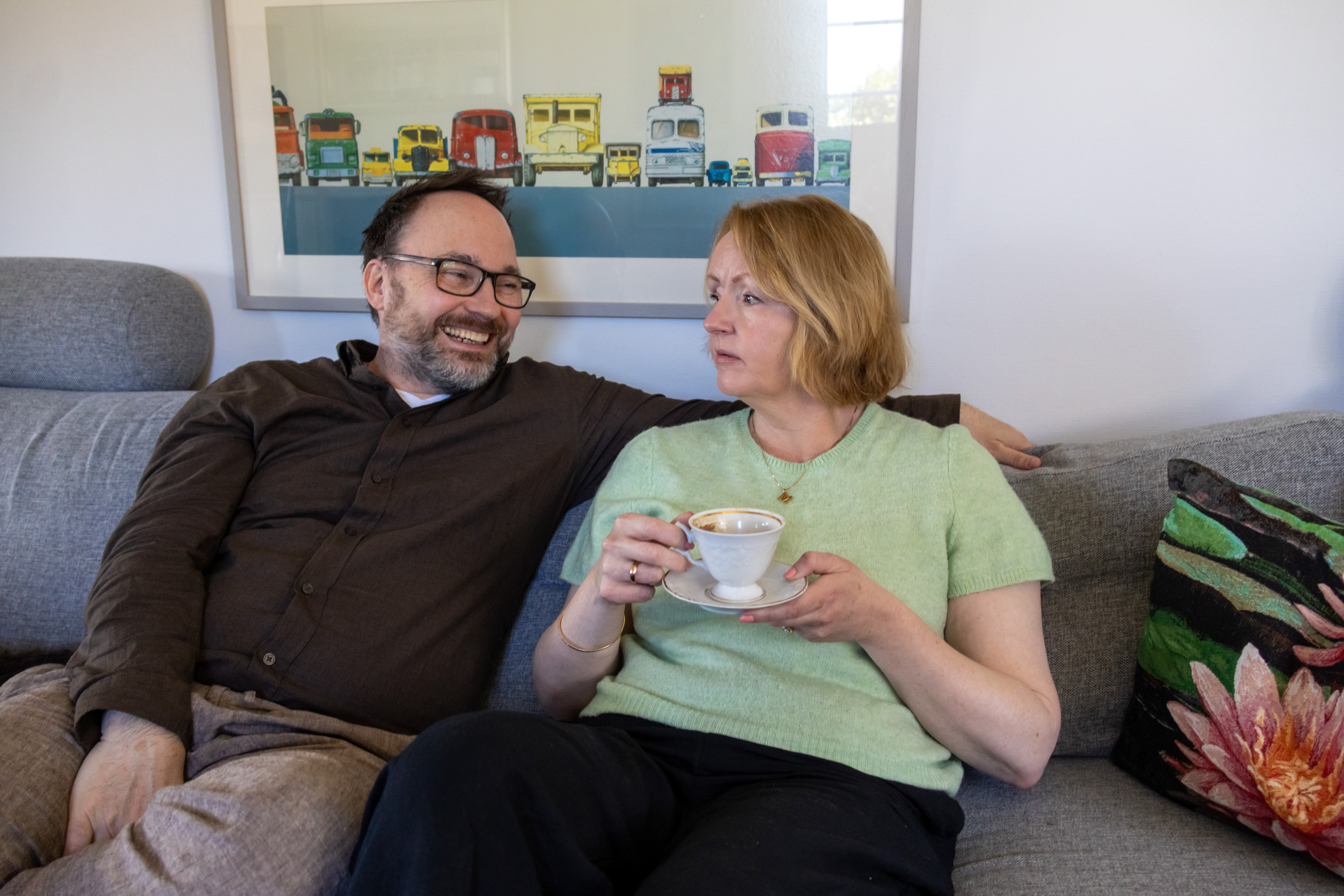 En kvinne og en mann sitter sammen i en sofa.