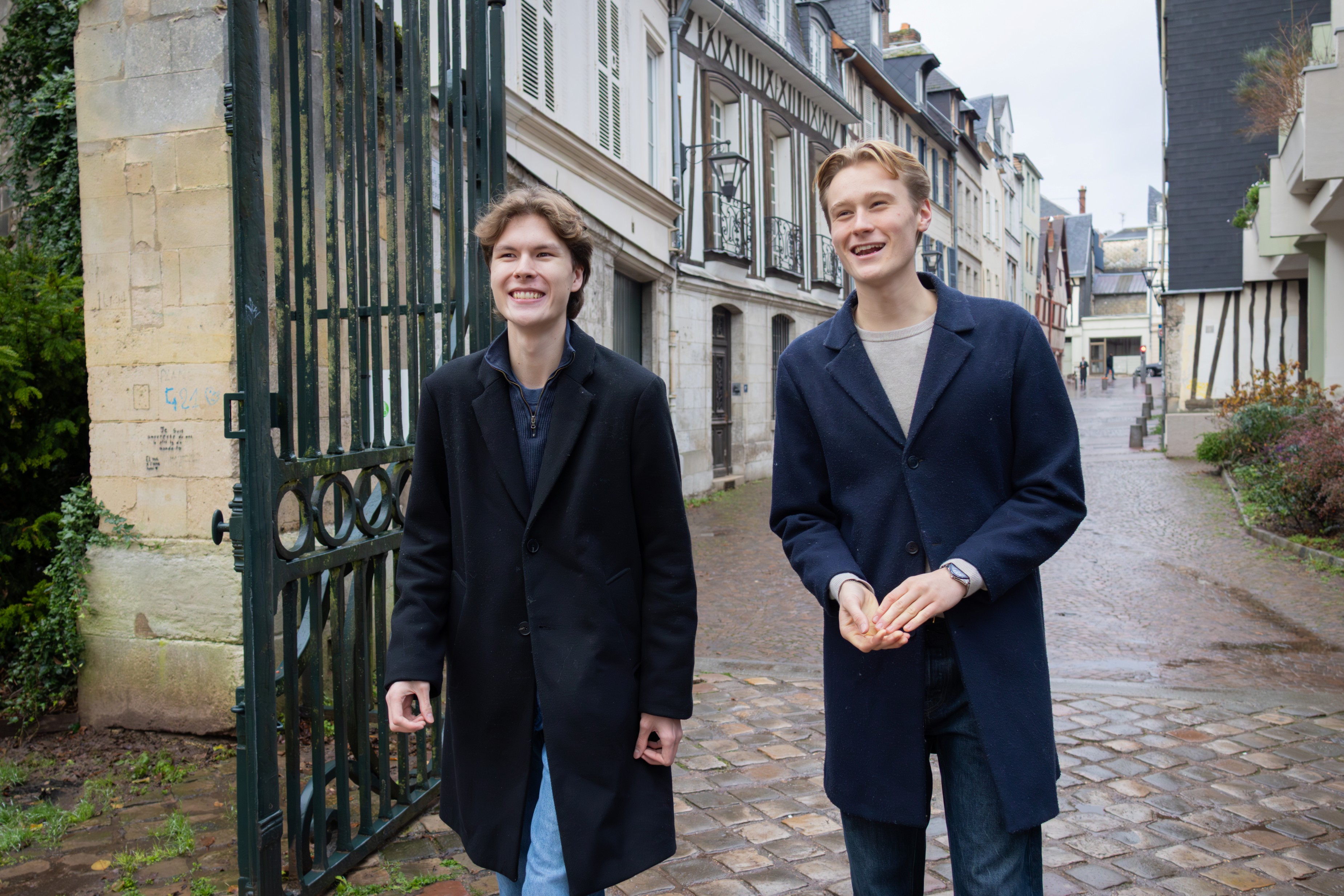 o unge menn går og prater i en brosteinsbelagt gate.