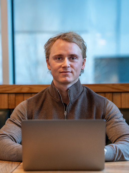 mann sitter ved et bord med laptop foran seg