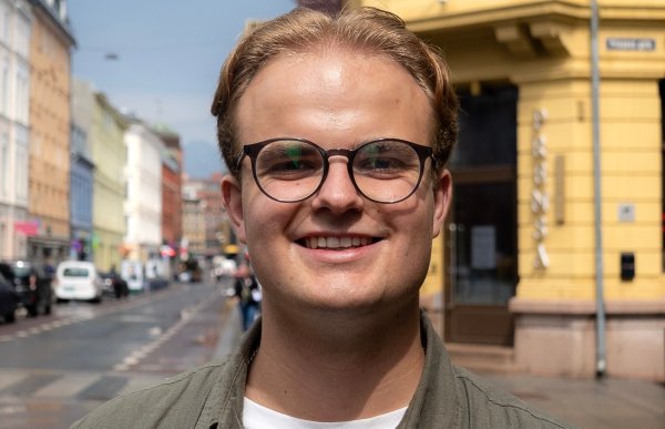 En mann i et grønn skjorte. Han smiler og ser rett i kameraet. 