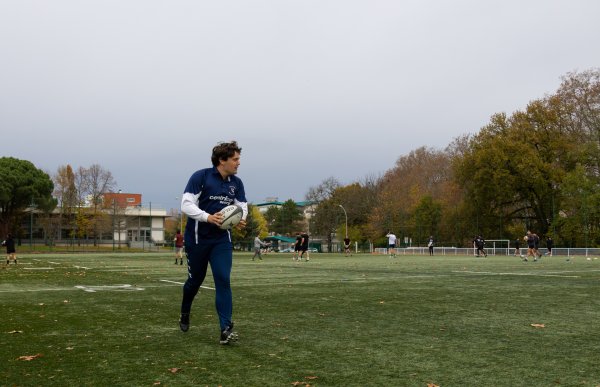 En ung mann spiller rugby på en grønn utendørs kunstgressbane. 