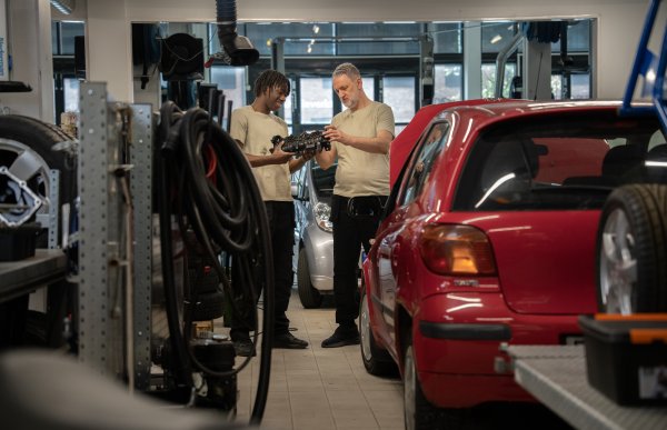 Ung mann får opplæring på bilverksted av voksen mann