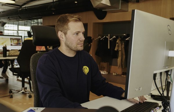 En mann i svart genser sitter foran en dataskjerm