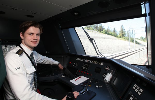 Ung mann i uniform i førerrommet på et lokomotiv.