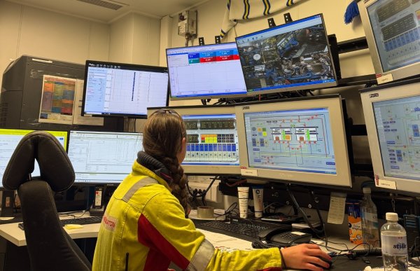 En offshorearbeider sitter foran en stor vegg av skjermer og kontrollsystemer i et kontrollrom på en plattform. Flere monitorer viser tekniske data, kameraovervåking og prosessdiagrammer knyttet til sementeringsoperasjoner.