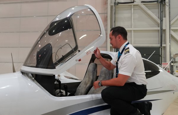 Mannlig flyinstruktør åpner luken på flyet før han skal sette seg i førersetet.