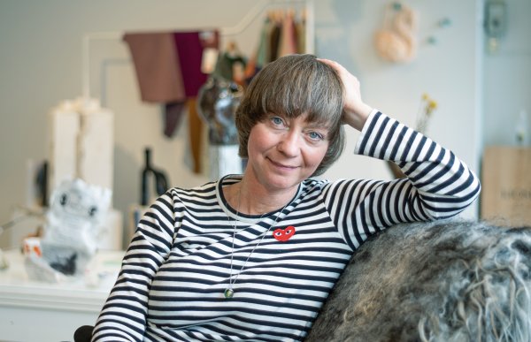 Kvinne i stripete genser sitter i en stol med ullteppe.