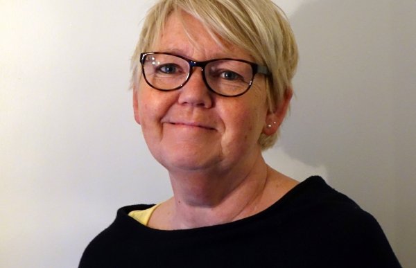 Portrettbilde av kvinne med briller og en mørk genser.