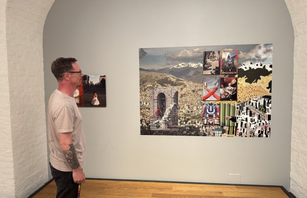 Mann med hvit t-skjorte og sort shorts står og ser på et bilde som henger på veggen inne i et museum.