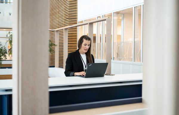 Kontor- og administrasjonsmedarbeider Tinecke Torsvik skriver på en data i et åpent landskap.