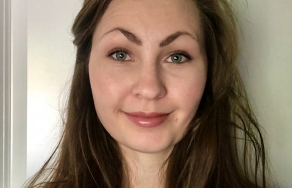 Ei dame med langt hår. Hun smiler og ser rett i kameraet. 