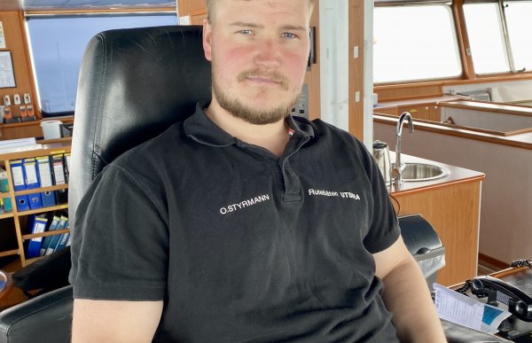 Overstyrmann Ken Roger Klovning er avbildet i styrhuset på M/S Utsira. Han er iført en svart piquet-trøye med o.styrmann i hvite bokstaver på brystet. 