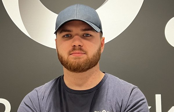 Ung mann med skjegg, svart t-skjorte og caps