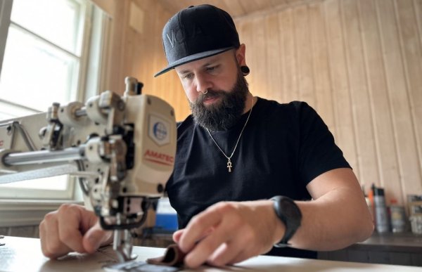 Mann med svart t-skjorte og caps sitter foran en symaskin.