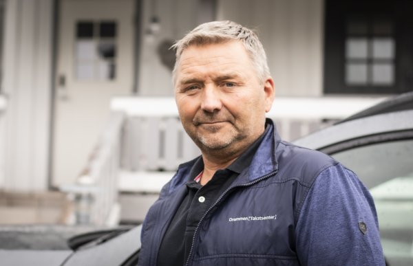 Mann i mørk vest og blå skjorte. Han ser rett i kameraet. Han er ute.