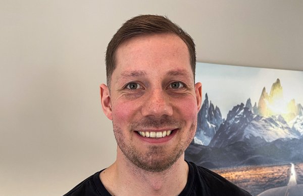 Portrettbilde av en mann i sort genser, med kort brunt hår.