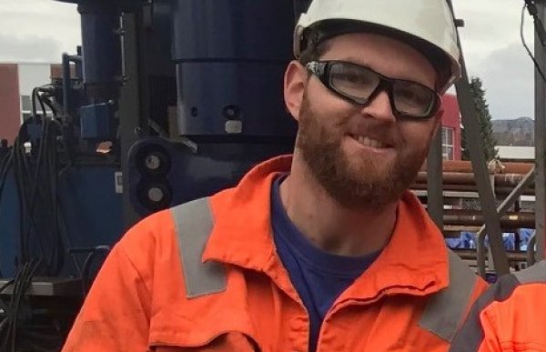 Brønnoperatør for mekaniske kabeloperasjoner Thomas Bjorland iført hjelm og orange kjeledress ute på plattform.