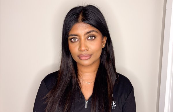 Kvinne med langt mørkt hår i svart langermet genser poserer foran kamera.