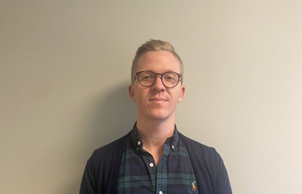 En mann med briller og mørke klær. Han ser rett i kameraet.