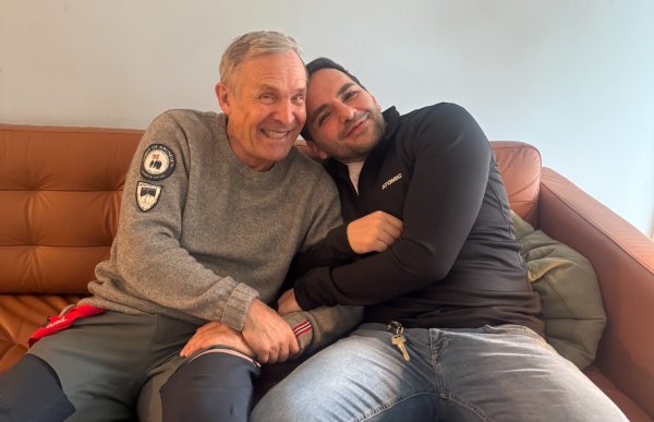 To menn sitter tett sammen i en sofa og smiler, den ene lener hodet mot den andre i en avslappet og trygg situasjon.