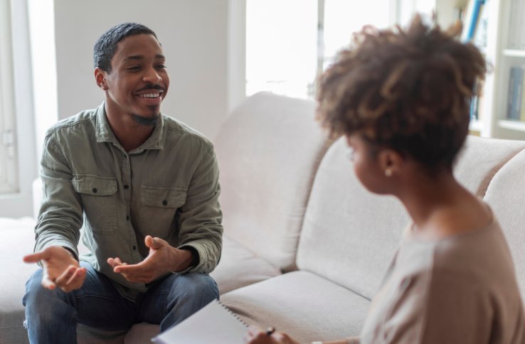 En mann og en kvinne sitter i en sofa og snakker sammen