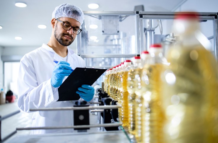 Mann med labfrakk og hårbånd følger med på produksjon av matolje Mann med labfrakk og hårbånd følger med på produksjon av matolje