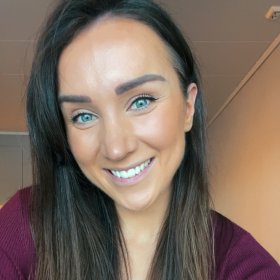 Dame med brunt hår smiler til kamera