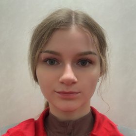 En kvinne med lyst brunt hår i hestehale og rød jakke på