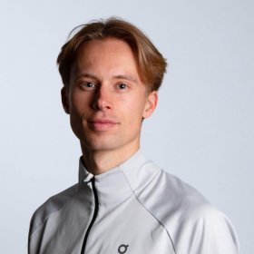 En mann med kort, blondt hår som har på seg en hvit jakke.