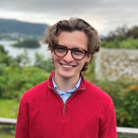 En mann i rød genser står utendørs.