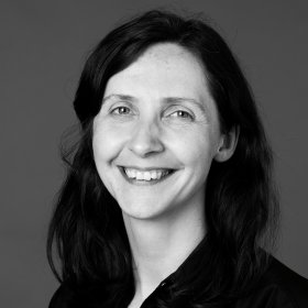 En smilende dame med mørkt hår. Bildet er i sort-hvitt. 