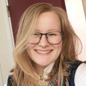 Lyshåret dame med briller og bunad smiler til kamera