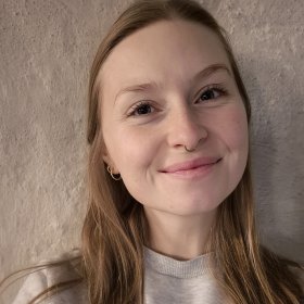 En kvinne med langt hår smiler til kamera. 