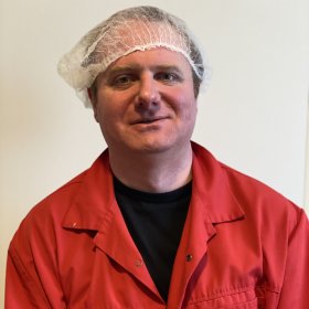 Portrettfoto av mann med hårnett og rød arbeidsfrakk