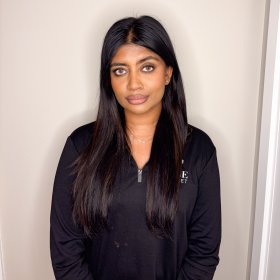 Kvinne med langt mørkt hår i svart langermet genser poserer foran kamera.