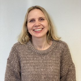 Evinne med blondt langt hår og brun ullgenser.