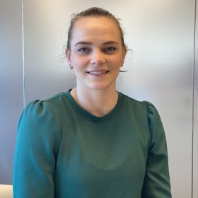 Ung kvinne med grønn kjole smiler mot kamera