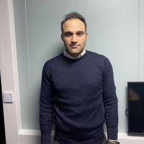 Sivilingeniør Jamal Haqi Mann med svart genser og mørkt hår står foran en kontorvegg
