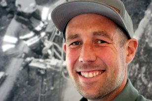 Smilende ung mann med grå caps og grå skjorte.