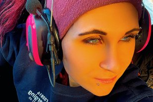 Dame med hørselvern og rosa lue sitter bak rattet i en bil