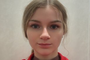 En kvinne med lyst brunt hår i hestehale og rød jakke på