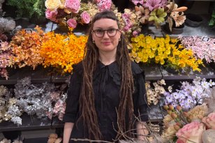 Kvinne med langt brunt hår, iført svart skjorte og briller, poserer foran kamera.