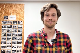 Portrettbilde av Animatør. Mann i rutete rød- og gulskjorte poserer foran kamera. I bakgrunnen skimtes en vegg med bilder fra kontorlandskapet.