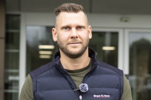 Joakim Starholm jobber som bilselger hos Birger N Haug Mann i grønn skjorte og blå vest smiler og ser inn i kameraet.