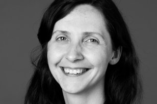 En smilende dame med mørkt hår. Bildet er i sort-hvitt. 