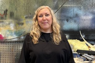 Rekvisitør Åshild Mjelde Nordås En kvinne med langt, krøllete blondt hår smiler mot kameraet. Hun har på seg en svart genser. Bak henne er en vegg full av ulike farger.