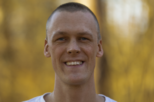 En mann i hvit t-skjorte smiler mot kamera