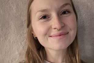 En kvinne med langt hår smiler til kamera. 