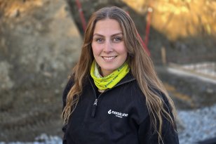 Kranfører Dorthe Sandvik Dame med lysebrunt hår løst, gul buff og svart jakke ser inn i kamera og smiler.