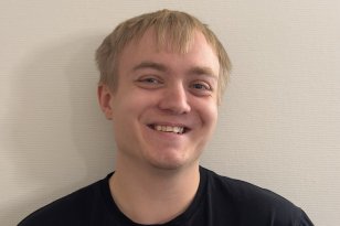 Lyshåret mann med svart t-skjorte står foran en hvit vegg